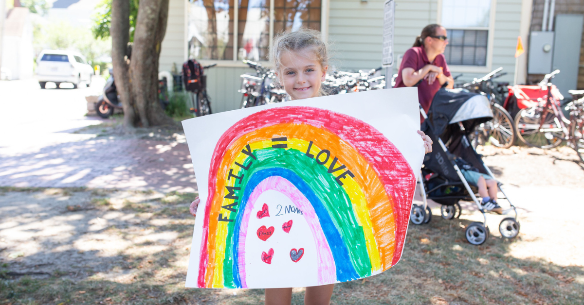 Child holding a sign that reads, "Family = love"