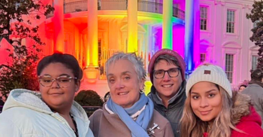 Family in front of the White House, which is colored in rainbow lights